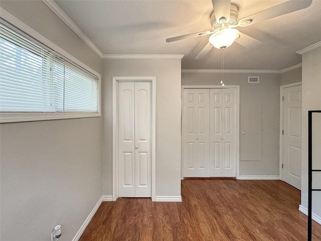 209 Lake Frst, Canyon Lake, TX 78133 - unfurnished bedroom with visible vents, wood finished floors, two closets, baseboards, and ceiling fan