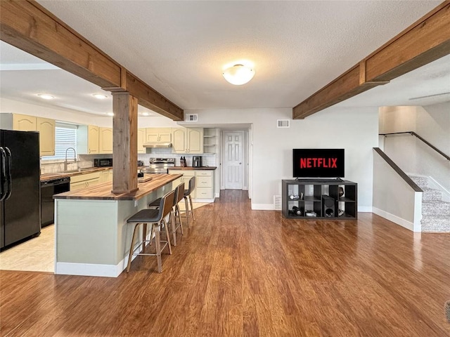 209 Lake Frst, Canyon Lake, TX 78133 - kitchen with wooden counters, beamed ceiling, black appliances, and wood finished floors