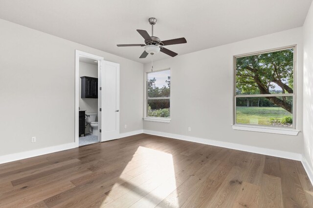 interior space featuring baseboards, ceiling fan, wood finished floors, and connected bathroom