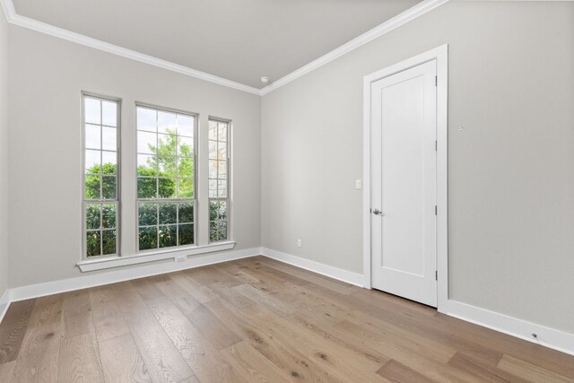 spare room with crown molding, baseboards, and wood finished floors