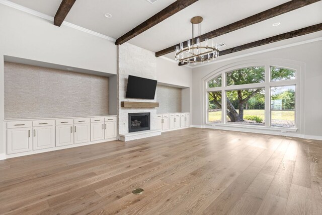 unfurnished living room with light wood finished floors, a chandelier, a large fireplace, baseboards, and beamed ceiling
