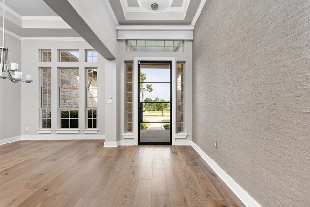 foyer featuring wood-type flooring, baseboards, crown molding, and a chandelier