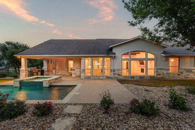 2120 High Lonesome Dr, Leander, TX 78641 - back of house at dusk with stone siding, a patio area, stucco siding, and roof with shingles