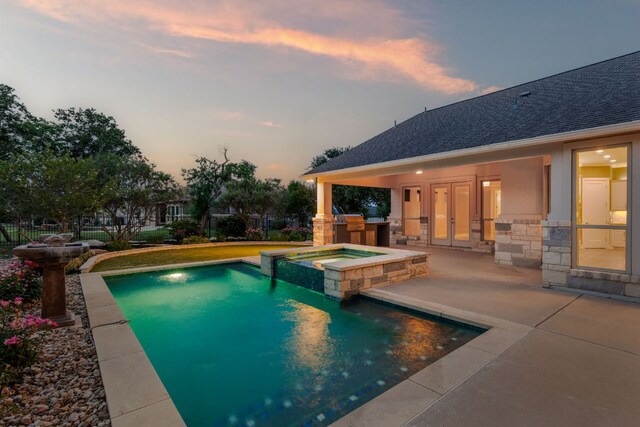 view of swimming pool with french doors, a pool with connected hot tub, a patio area, fence, and an outdoor kitchen