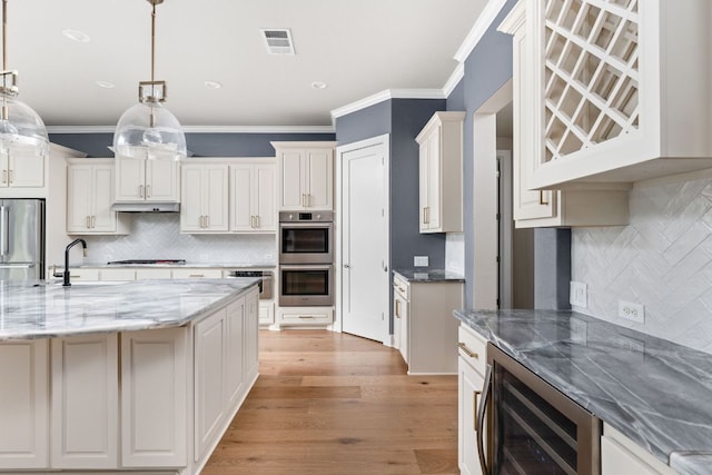 2120 High Lonesome Dr, Leander, TX 78641 - kitchen with appliances with stainless steel finishes, beverage cooler, tasteful backsplash, crown molding, and light wood-style floors