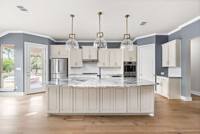kitchen with a spacious island, baseboards, appliances with stainless steel finishes, and visible vents