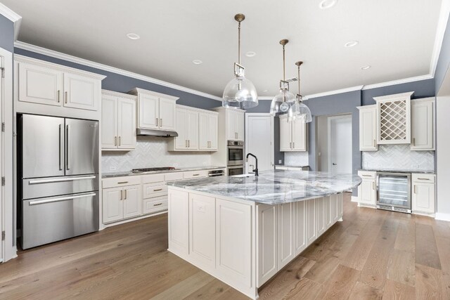kitchen featuring crown molding, stainless steel appliances, decorative backsplash, wine cooler, and under cabinet range hood