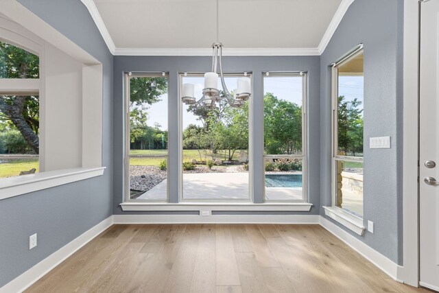 unfurnished dining area with crown molding, baseboards, wood finished floors, and a chandelier