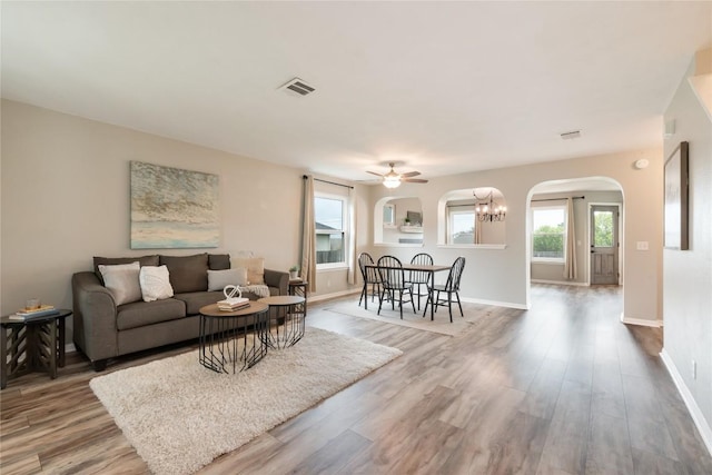 234 Saint Marys Dr, Hutto, TX 78634 - living room featuring visible vents, wood finished floors, baseboards, arched walkways, and ceiling fan with notable chandelier