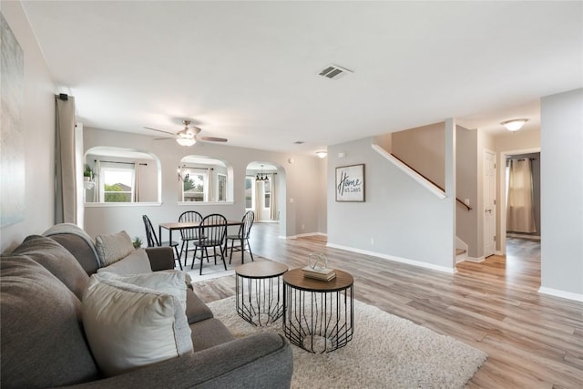 234 Saint Marys Dr, Hutto, TX 78634 - living area with ceiling fan, light wood-style floors, arched walkways, stairs, and visible vents