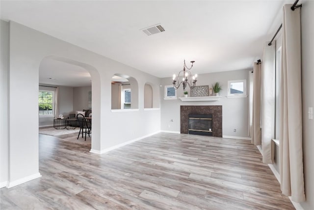 234 Saint Marys Dr, Hutto, TX 78634 - unfurnished living room with visible vents, a fireplace, light wood-type flooring, baseboards, and an inviting chandelier