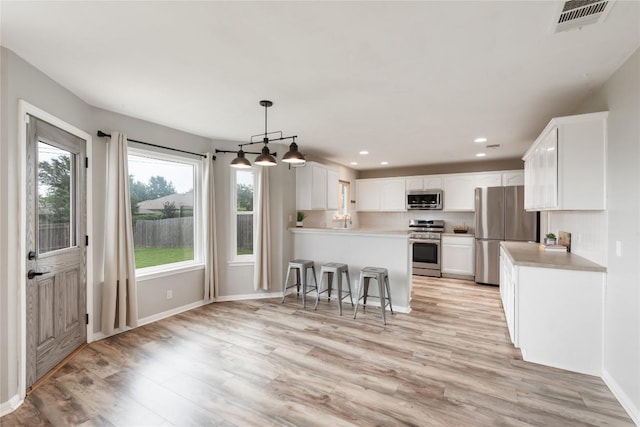 234 Saint Marys Dr, Hutto, TX 78634 - kitchen featuring stainless steel appliances, visible vents, light wood-style flooring, and a peninsula
