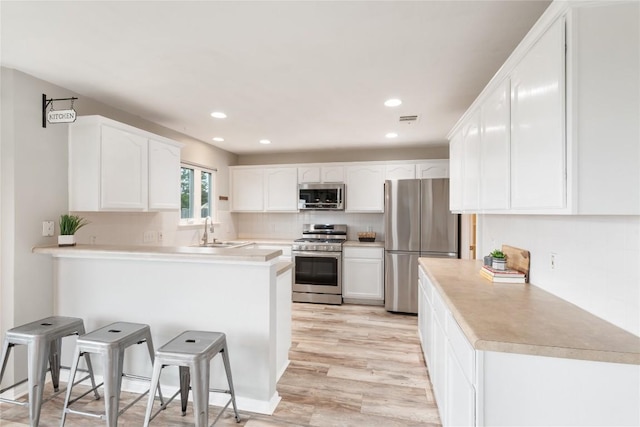 234 Saint Marys Dr, Hutto, TX 78634 - kitchen with visible vents, appliances with stainless steel finishes, white cabinets, a peninsula, and recessed lighting