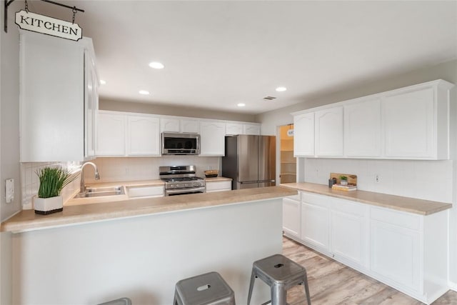 234 Saint Marys Dr, Hutto, TX 78634 - kitchen featuring decorative backsplash, a sink, white cabinets, a peninsula, and stainless steel appliances