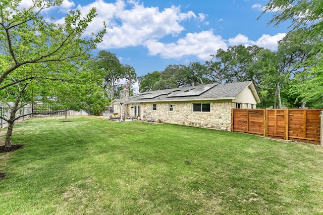 11600 Eubank Dr, Austin, TX 78758 - rear view of property with stone siding, solar panels, a fenced backyard, a chimney, and a patio area