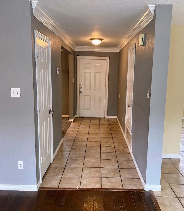 hallway with crown molding, light tile patterned floors, and baseboards