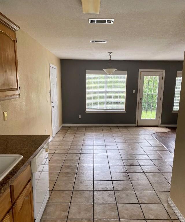 unfurnished dining area featuring baseboards, visible vents, and light tile patterned floors