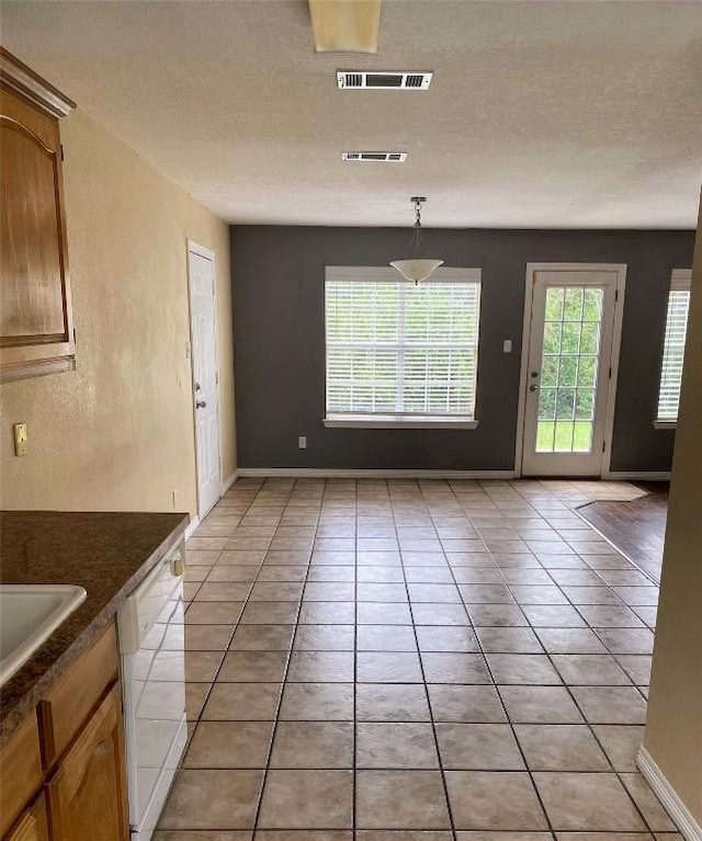 619 Ellen Ct, Temple, TX 76501 - unfurnished dining area featuring light tile patterned floors, baseboards, a textured ceiling, and a sink