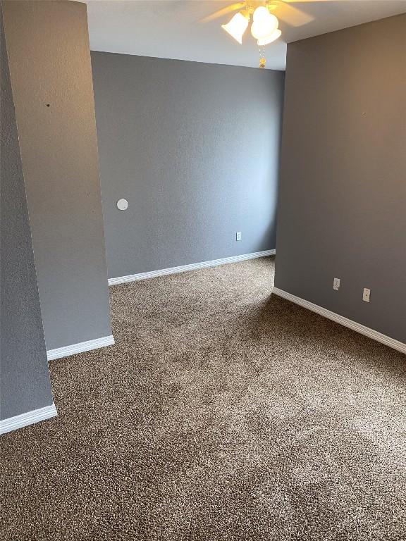 carpeted spare room with ceiling fan and baseboards
