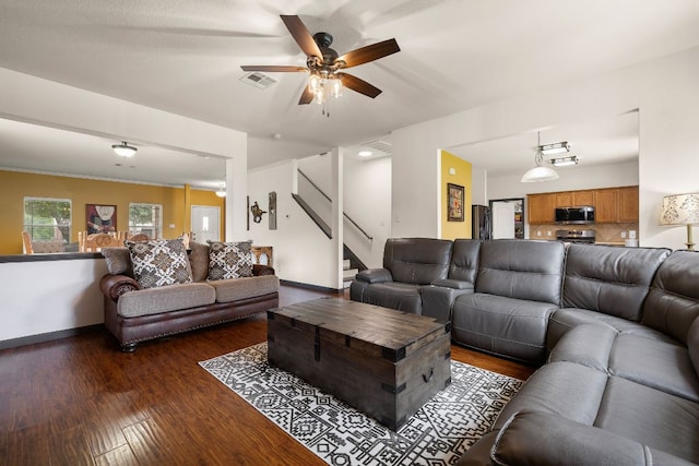 living room featuring ceiling fan, stairs, baseboards, visible vents, and dark wood-style floors