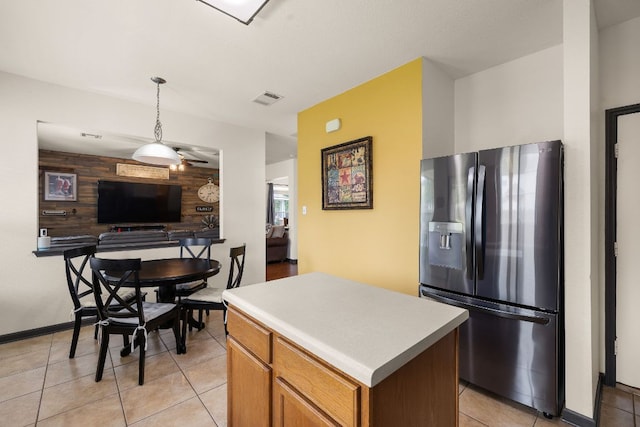 kitchen with visible vents, a center island, hanging light fixtures, stainless steel fridge, and light tile patterned flooring