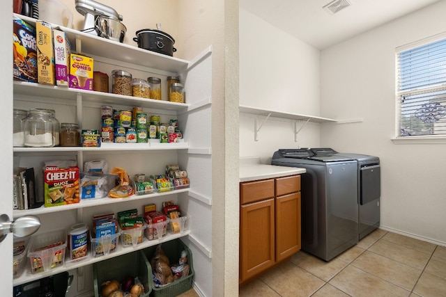 washroom featuring washing machine and clothes dryer, baseboards, visible vents, and light tile patterned floors