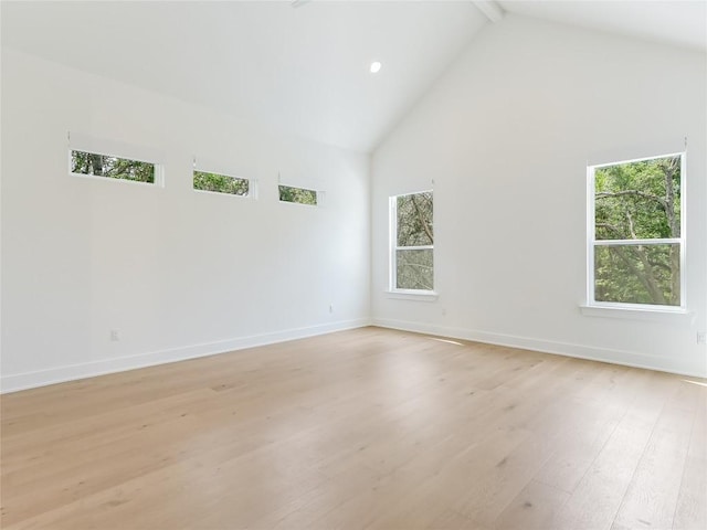 empty room with baseboards, high vaulted ceiling, a wealth of natural light, and light wood finished floors