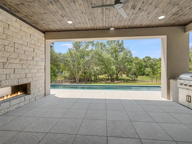 view of swimming pool featuring grilling area, ceiling fan, a patio area, fence, and an outdoor brick fireplace