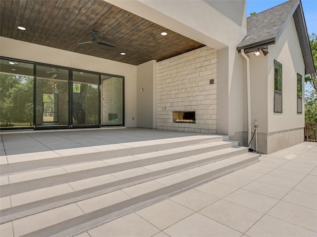 view of patio with ceiling fan and a large fireplace
