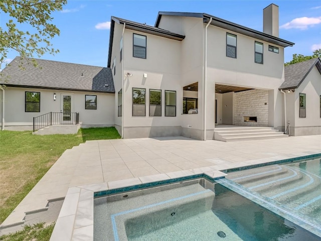 back of property featuring a patio, an in ground hot tub, a chimney, and stucco siding