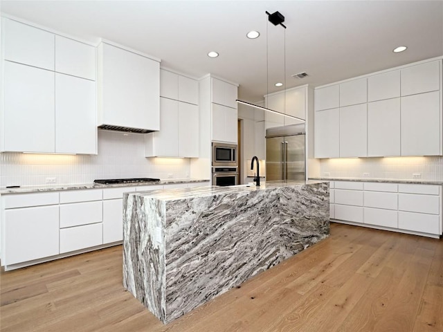 kitchen featuring built in appliances, tasteful backsplash, modern cabinets, and light wood-style floors
