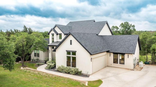 view of front facade with a garage, roof with shingles, stucco siding, a standing seam roof, and concrete driveway