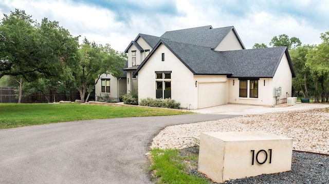 modern inspired farmhouse featuring fence, a shingled roof, a garage, stucco siding, and a front yard