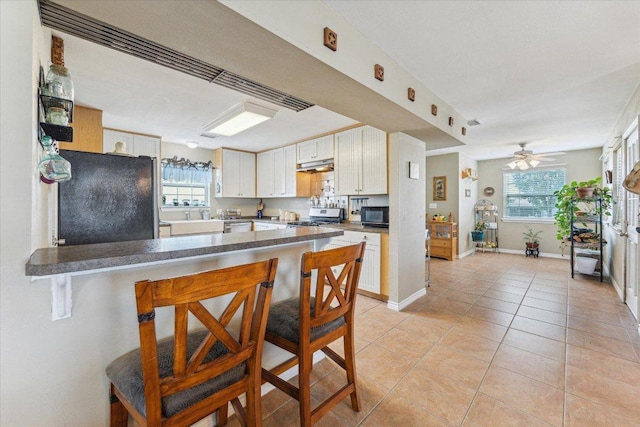 2334 County Road 464, Elgin, TX 78621 - kitchen featuring freestanding refrigerator, black microwave, a kitchen breakfast bar, light tile patterned floors, and range