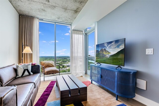 living room with a wall of windows and wood finished floors