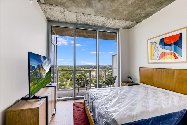 bedroom featuring floor to ceiling windows, access to exterior, and wood finished floors