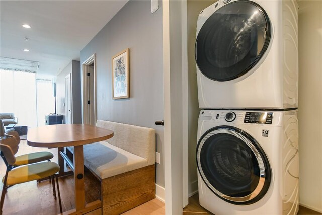 laundry area with laundry area, stacked washer / dryer, baseboards, recessed lighting, and light wood finished floors