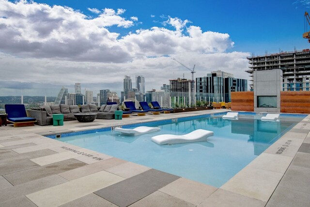 pool featuring a view of city, a fire pit, and a patio area