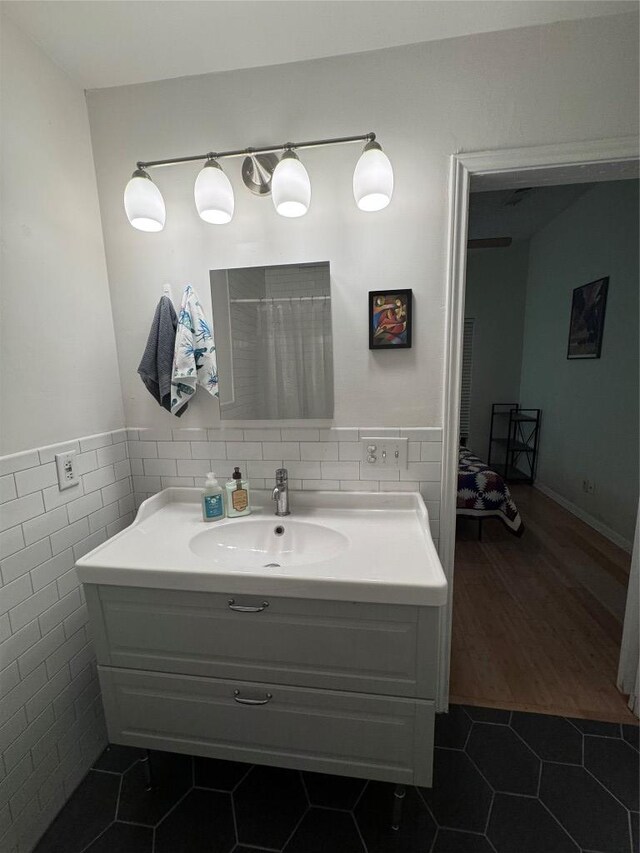 full bathroom featuring tile patterned floors, tile walls, wainscoting, and vanity