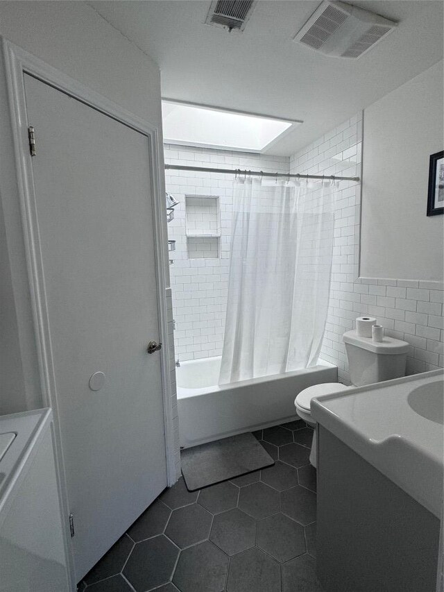 full bathroom with toilet, visible vents, tile walls, and shower / bath combo