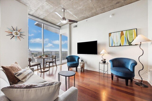 living area featuring visible vents, baseboards, a wall of windows, and hardwood / wood-style flooring