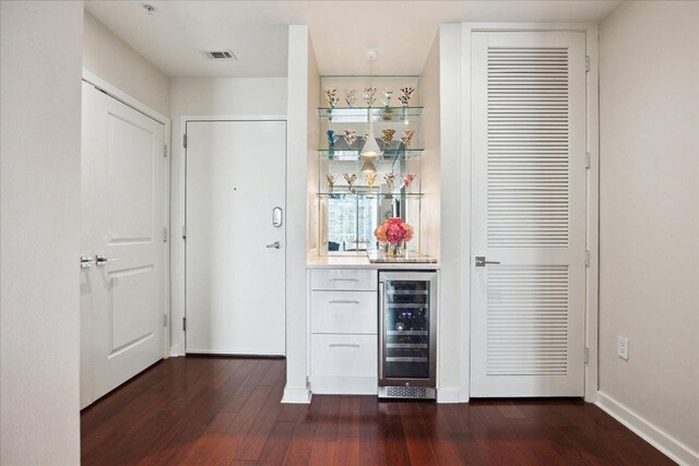 bar featuring visible vents, dark wood finished floors, baseboards, wine cooler, and bar area