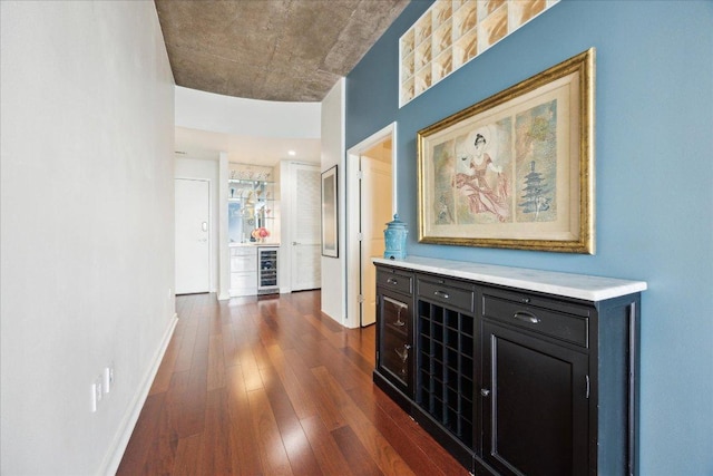 corridor featuring baseboards, dark wood finished floors, and wine cooler