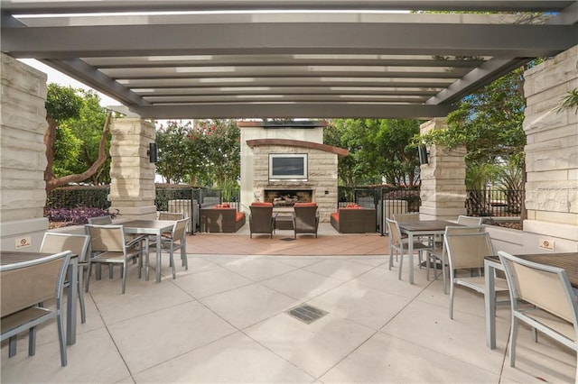 view of patio featuring an outdoor stone fireplace, fence, outdoor dining area, and a pergola