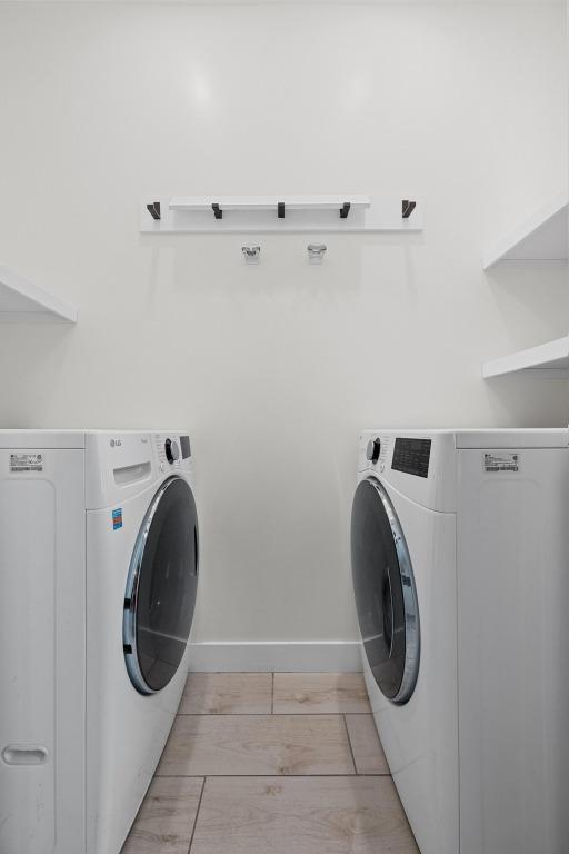 laundry room featuring laundry area, washing machine and dryer, and light wood-style flooring