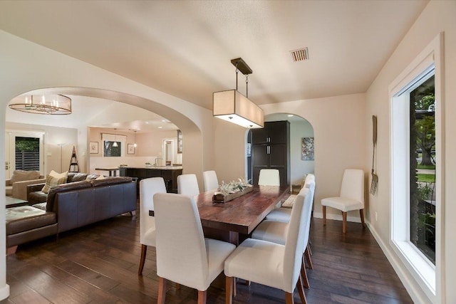 dining space with dark wood-style flooring, arched walkways, baseboards, and visible vents