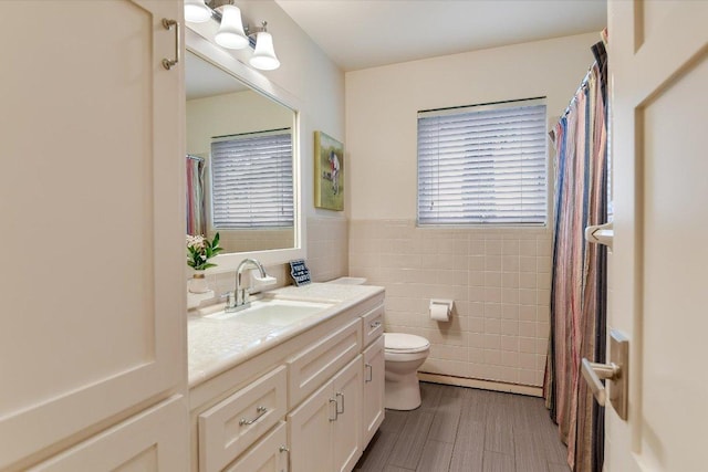 full bath with vanity, a healthy amount of sunlight, toilet, and tile walls