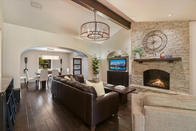 living area featuring a stone fireplace, visible vents, arched walkways, dark wood-style floors, and vaulted ceiling with beams