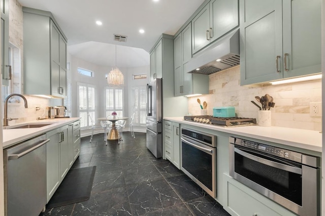 3605 Fawn Creek Path, Austin, TX 78746 - kitchen featuring appliances with stainless steel finishes, under cabinet range hood, decorative backsplash, light countertops, and a chandelier
