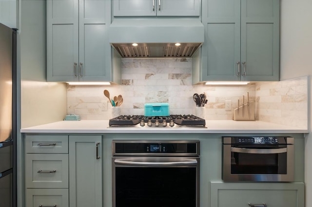 3605 Fawn Creek Path, Austin, TX 78746 - kitchen with wall chimney exhaust hood, stainless steel appliances, light countertops, and decorative backsplash